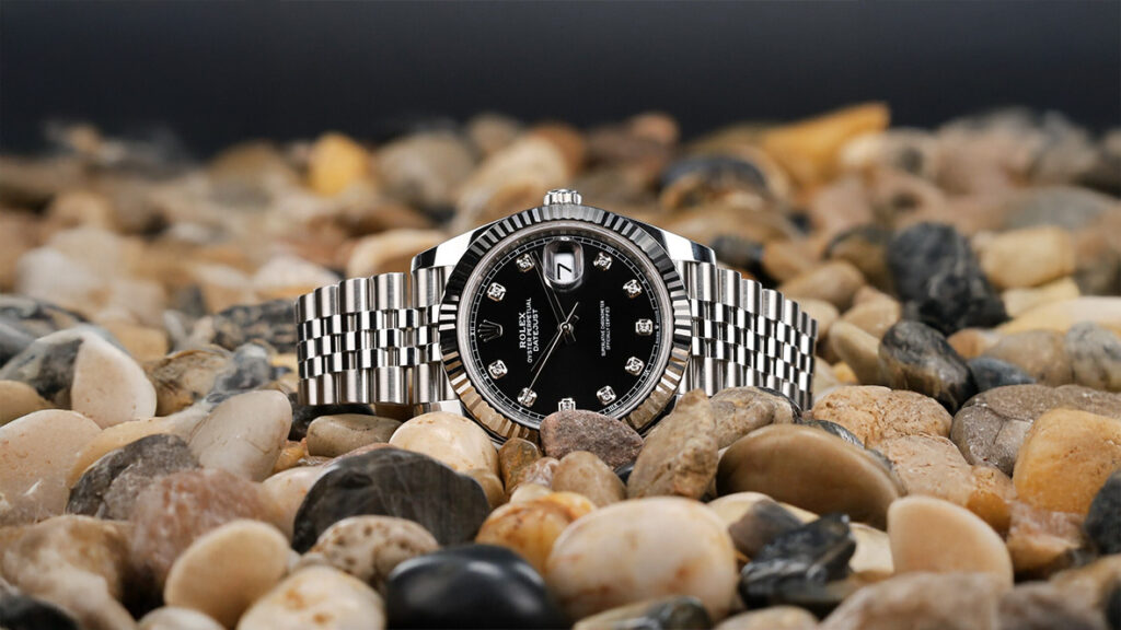 datejust 41 black diamond watch amid decorative rocks on laying on the side